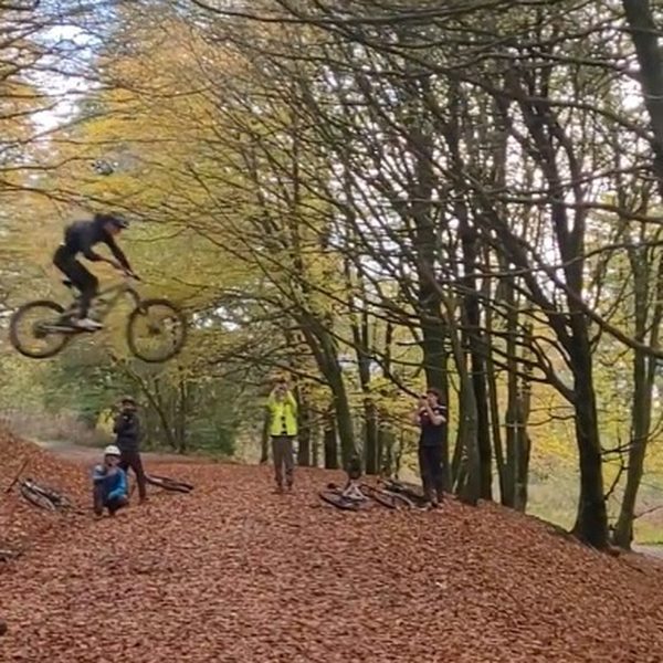 A club member mid-air over an autumn woodland jump